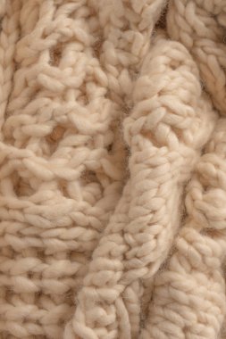 A fragment of beige knitted fabric, knitted from white sheep wool. Knitted background. 