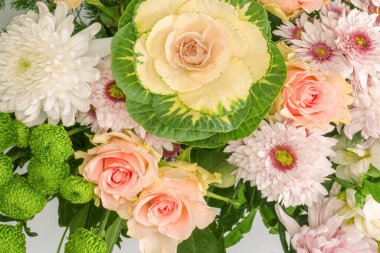 Üzerinde pembe güller olan bir buket çiçek, brassica çiçeği, kasımpatı ve frezya çiçeği beyaz bir arkaplanda izole edilmiş vazoda.. 