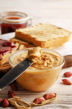 Cam kaseye düşük açılı bir bakış açısı beyaz ahşap masada fıstık ezmesi ve reçel. Sağlıklı yeme kavramı