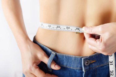 Onun düz mide gösteren bant ölçümü ile mavi kot beyaz kadın modeli. Sağlıklı yaşam tarzı ve weightloss kavramı.