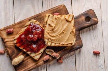Fıstık ezmeli ve reçelli sandviçleri kesme tahtasının üzerinde düz bir şekilde duruyordu. Sağlıklı yeme kavramı