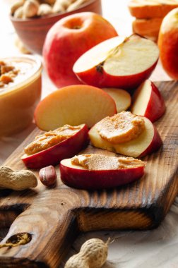 Tahtayı, beyaz ahşap mutfak masasında fıstık ezmeli elma dilimleriyle kes.