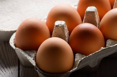 Eko Dostu kağıt karton beyaz mutfak ahşap masa üzerinde ham organik kahverengi tavuk yumurta