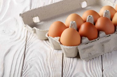 Eko Dostu kağıt karton beyaz mutfak ahşap masa üzerinde ham organik kahverengi tavuk yumurta