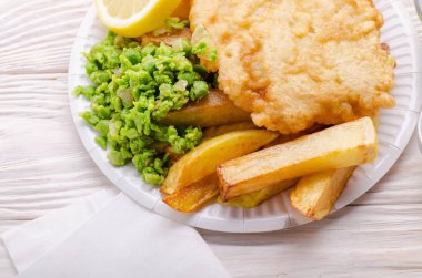 Geleneksel İngiliz sokak gıda balık ve patates kızartması ile kağıt tabakta duygusal bezelye