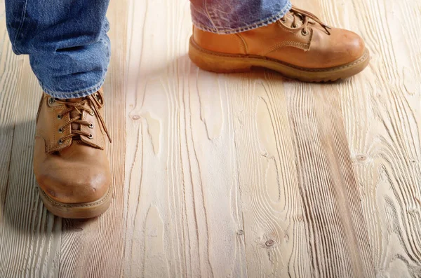 Carpenter feet in work boots standing on wooden floor. Place for text