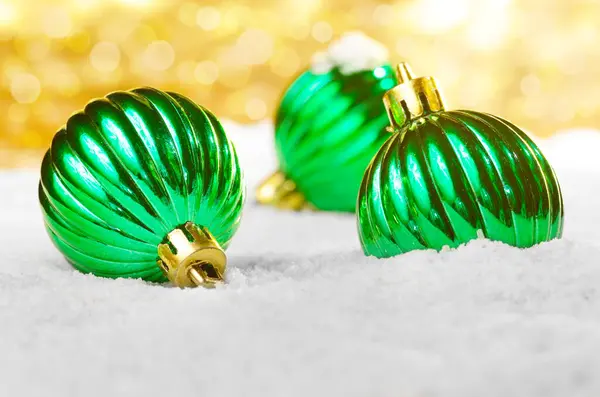 Grüne Weihnachtskugeln Auf Dem Schnee Vor Goldenem Hintergrund — Stockfoto