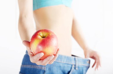 Kırmızı elma onu düz mide gösteren mavi kot beyaz kadın modeli. Sağlıklı yaşam tarzı ve weightloss kavramı.