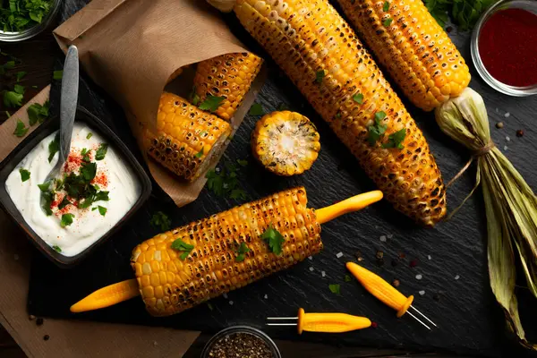 烤玉米放在玉米芯上 放在厨房木桌的背景上 用高加索人的手烤 — 图库照片