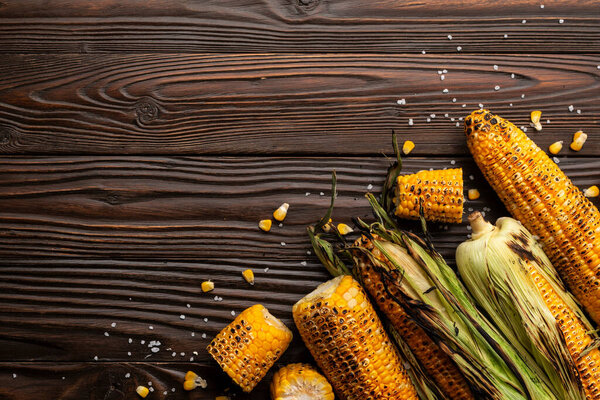 Grilled corn on the cob on kitchen wooden table flat lay background with copyspace