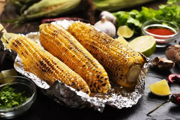 厨房桌子上的锡箔烤玉米健康的无麸质食物背景 图库照片