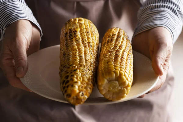 白人男性的手拿着烤着甜玉米的盘子 图库照片