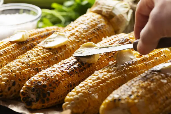 放在桌上的烤甜玉米芯 用黄油调料调味 角度低 图库照片