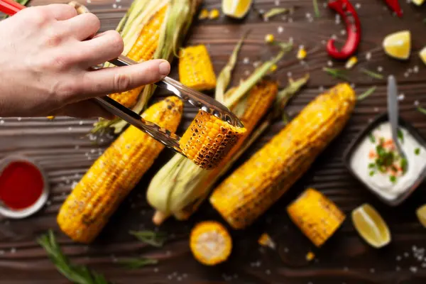 Kitchen Tongs Grilled Corn Cob Pieces Caucasian Hands Kitchen Wooden Royalty Free Stock Images