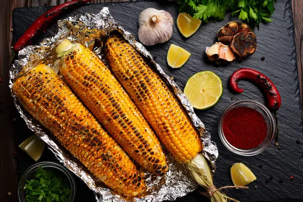 厨房桌子上的锡箔烤玉米健康的无麸质平铺食物背景 免版税图库照片