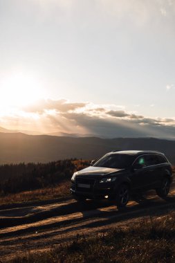 Araba kamyonu gün batımında dağlarda yola çıkıyor.