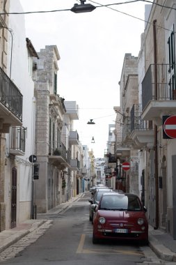 Polignano ve Mare küçük şehir caddesi, park etmiş arabaları ve insanları yok. Güneşli sakin bir gün. Taştan evleri olan eski bir ortaçağ kasabası