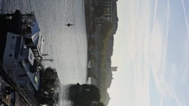 Paris 'in arka planında bir gemi ve kemer köprüsü olan Seine Nehri' nin kıyısında dikey bir görüntü. # Boş güneşli bir sabah #