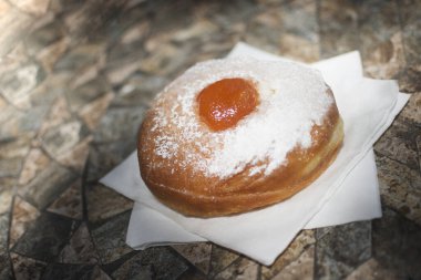 Traditional donut with apricot jam and sugar powder on napkins on the table. clipart