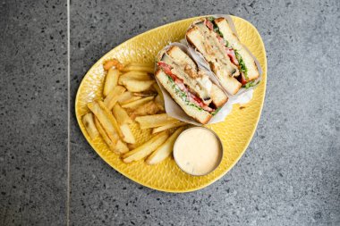 Akşam yemeğinde peynirli, etli ve kızarmış patatesli sandviç.