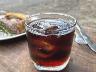 Cola drink with ice cubes and beef steak grilled