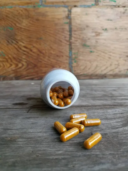 Turmeric capsule on wood background