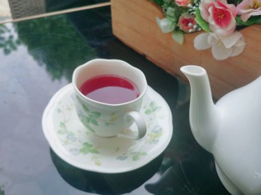 Pembe güllü çay çiçekleri ve masada fincanlar