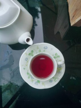 Pembe güllü çay çiçekleri ve masada fincanlar