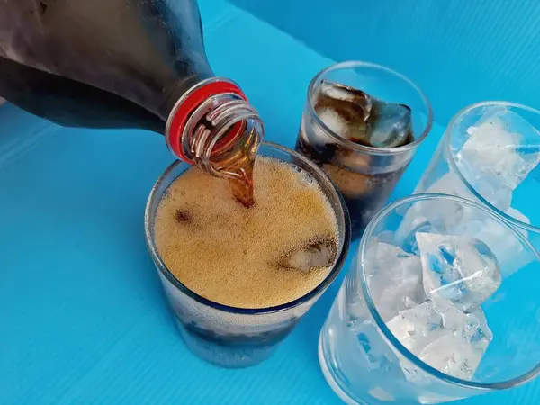 Verter Bebida Cola Sobre Vaso Con Hielo Sobre Fondo Azul Imagen De Stock
