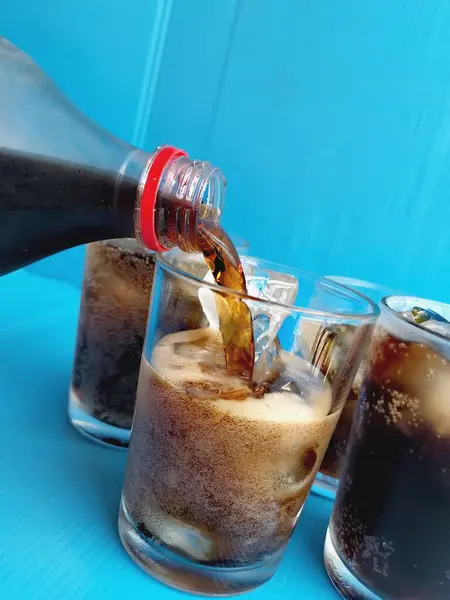Verter Bebida Cola Sobre Vaso Con Hielo Sobre Fondo Azul Imagen De Stock