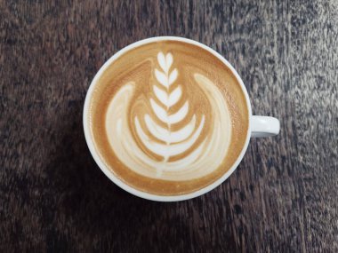 Kahverengi ahşap masada Latte sanatı