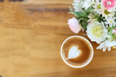 Süt köpüklü kahve ve yapay çiçekler.