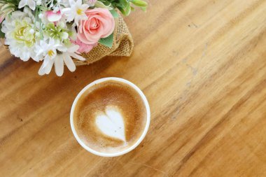 Süt köpüklü kahve ve yapay çiçekler.