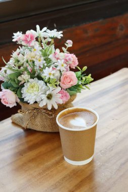 Süt köpüklü kahve ve yapay çiçekler.
