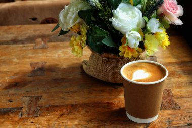 Süt köpüklü kahve ve yapay çiçekler.