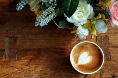 Süt köpüklü kahve ve yapay çiçekler.