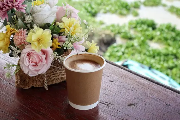 Süt köpüklü kahve ve yapay çiçekler.