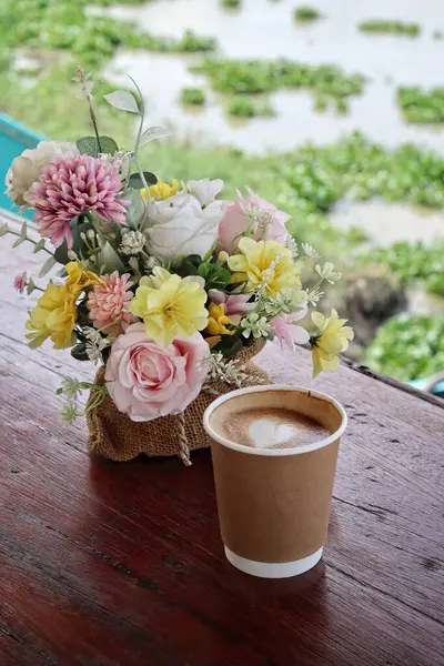 Süt köpüklü kahve ve yapay çiçekler.