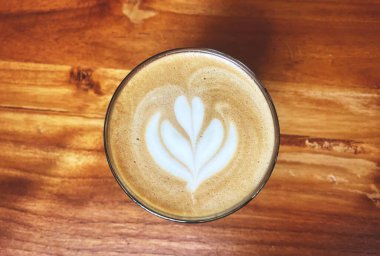 Kahverengi ahşap masada Latte sanatı