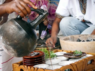 Woman pouring coffee in cups as part of a traditional coffee ceremony performed in Ethiopia, Africa.