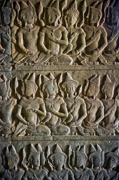 Sitting male characters carved into an ancient Khmer temple in Angkor Wat, Cambodia