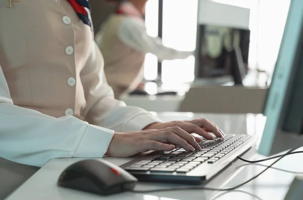 Airline attendant woman working at check-in desk at airport. Close up of woman hand typing on PC computer keyboard.