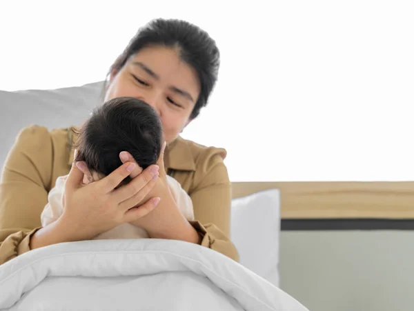 stock image Baby head in mother hands. Happy asian mom sitting and nursing infant baby on bed. Love, Health Care and mothers day concept