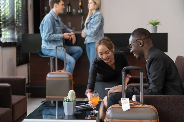 Airport lounge waitress serving orange juice to African businessman passenger. Black male waiting for his flight.
