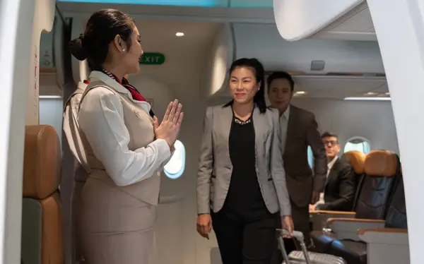 Air hostess or cabin crew standing at airplane entrance door. Flight attendant greeting for business passengers leaving airplane cabin. Airline transportation and tourism concept.