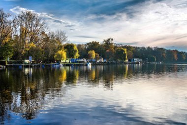 Güz mevsiminde güzel bulutlar ve renkli ağaçlarla dolu bir nehir.