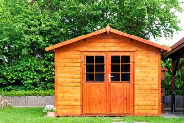 Frontal view of wooden garden shed glased in teak color clipart