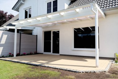 Güneşli bir günde ahşap verandalı küçük klasik aile evine yan bakış.