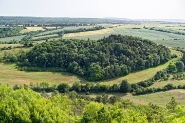 Nefes kesen panoramik bir manzara ormanı kalp şeklinde, yemyeşil tepeler ve açık mavi gökyüzünün altındaki geniş geniş alanları gösteriyor. Görüntü: Veste Wachsenburg