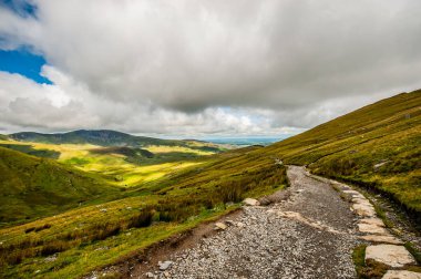 Bir yolu ve bulutu olan güzel bir dağ manzarası